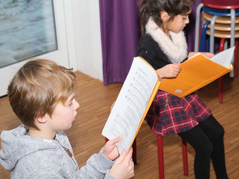 zwei Grundschul Kinder mit Chor Noten